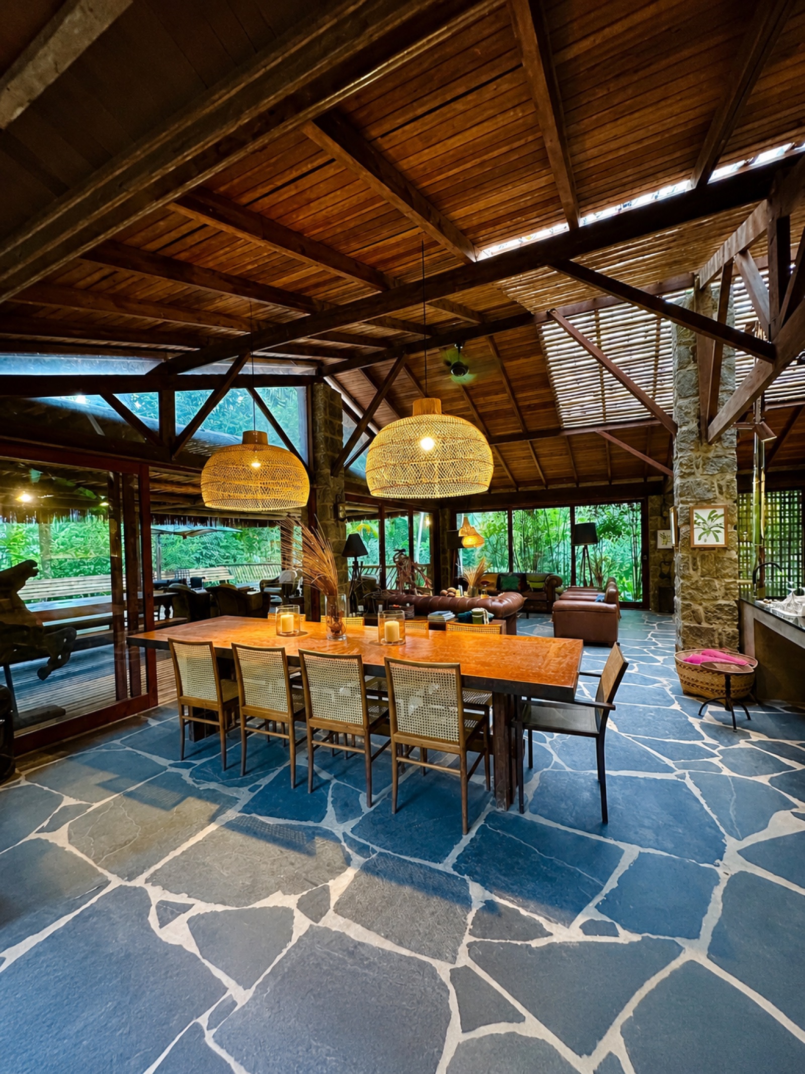 Warm wooden gathering room with a long dining table and forest views